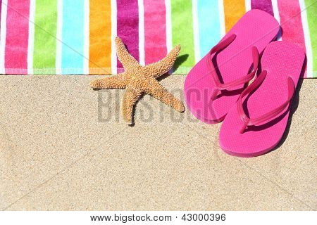 Picture or Photo of Tropical beach vacation holiday and travel concept with a colourful striped beach towel and vibrant pink sandal flip flip thongs on pristine sand with a starfish at an idyllic coastal beach resort.
