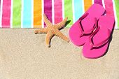 stock photo of beach  - Tropical beach vacation holiday and travel concept with a colourful striped beach towel and vibrant pink sandal flip flip thongs on pristine sand with a starfish at an idyllic coastal beach resort - JPG 