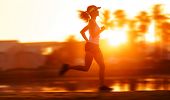 pic of fitness  - silhouette with motion blur of a woman athlete running at sunset or sunrise - JPG 