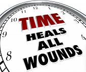 stock photo of time  - The saying Time Heals All Wounds on the face of a clock illustrating the forgiveness and resolved disputes that only the passing of time can bring about - JPG 