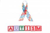 image of spell  - Autism awareness ribbon above letter blocks spelling autism on white background - JPG 