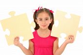 foto of puzzle  - Beautiful 7 year old girl holding two large puzzle pieces over white background - JPG 