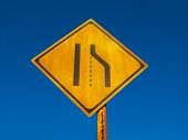 picture of merge  - Old and grungy road narrows sign or lane merge sign against a deep blue  sky background - JPG 