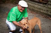 image of dog  - An elderly Hispanic senior citizen man petting his dog with a large smile on his face - JPG 