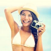 pic of blue  - Beach woman with vintage retro camera having fun playful laughing in bikini on blue ocean background wearing beach hat - JPG 