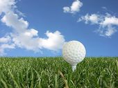 picture of golf  - white golf ball on a tee in grass over blue sky  - JPG 