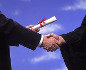 image of handshake  - A college graduate in cap and gown receives a diploma and a handshake
 - JPG 