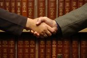 stock photo of handshake  - a handshake between two people with law books - JPG 