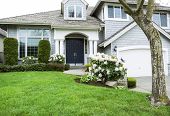 picture of home  - Horizontal photo of modern home in North American Suburbs with plush green grass rhododendron and tulips flower in mid spring season - JPG 