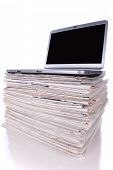 picture of newspaper  - Laptop over a stack of newspapers for internet information access  - JPG 