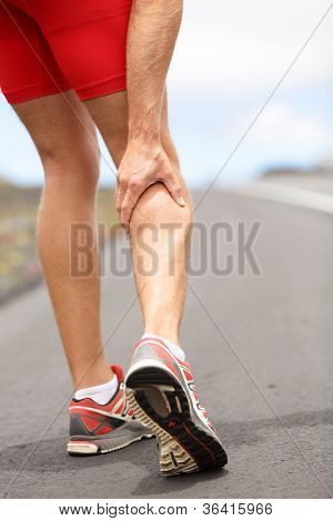 Picture or Photo of Cramps in leg calves or sprain calf on triathlete runner. Sports injury concept with running man.