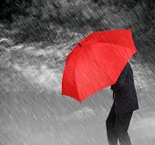 pic of finance  - Businessman with red umbrella protecting himself from the storm concept for protection from recession or economic depression etc - JPG 