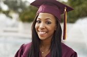 picture of  photo  - Attractive smiling young woman wearing graduation cap and gown - JPG 