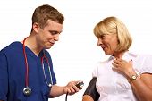 picture of pressure  - Doctor in scrubs taking the blood pressure of a mature female patient - JPG 