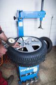 picture of pressure  - Auto mechanic in a garage checking the air pressure in a tyre with a pressure gauge   - JPG 