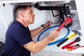 picture of workforce  - Young handsome plumber doing reparation at the kitchen - JPG 