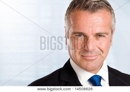 Picture or Photo of Closeup portrait of satisfied mature businessman in his office with copy space