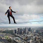stock photo of balancing  - Business man balancing high over a cityscape - JPG 