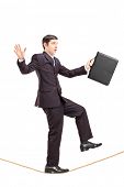 picture of steady  - Full length portrait of a businessman with briefcase walking on a rope isolated on white background - JPG 