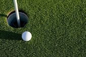 picture of golf  - A white golf ball near the hole of a golfing green or course - JPG 