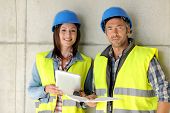 stock photo of construction  - Construction team standing against building wall with blueprint - JPG 