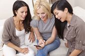 picture of laughing  - Three beautiful young women friends at home using a smart phone and laughing - JPG 