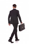 image of man  - back view of a walking business man holding a briefcase and looking to his side on white background - JPG 