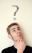 pic of wonder  - Young white Caucasian male wondering with a question mark above his head on the wall behind him - JPG 