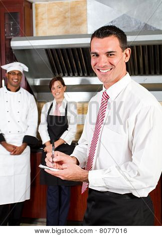 Picture or Photo of Young happy male restaurant manager and his staff in kitchen