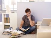 picture of home  - College student boy studying at home surrounded by books - JPG 