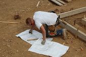 picture of construction worker  - Contruction worker looking at plans at foundation - JPG 
