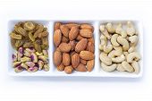 Dried fruits and variety of nuts in a bowl on the white table background, such as almonds, raisins, cashews, and pistachio. with copy space for your text.