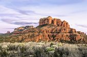 The setting sun paints the sky and rock formations of Sedona, Arizona including Cathedral Rock to the right.