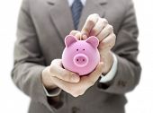 image of investment  - Businessman putting coin into the piggy bank - JPG 