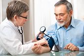 stock photo of pressure  - doctor measuring blood pressure of male patient - JPG 
