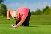 stock photo of golf  - Young female golf player on course aiming for her put - JPG 