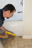 picture of seep  - Contractor sealing tub base to keep water from seeping through the ceramic tile and rotting the floor - JPG 
