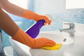 foto of home  - woman doing chores in bathroom at home cleaning sink and faucet with spray detergent - JPG 