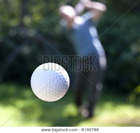 Picture or Photo of A golf ball just coming off the tee from a golfer in swing.