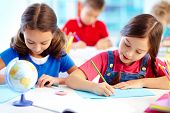 foto of youngster  - Portrait of lovely girls drawing at workplace with schoolboys on background - JPG 