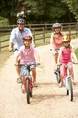 image of family  - Family Cycling In Countryside Wearing Safety Helmets - JPG 