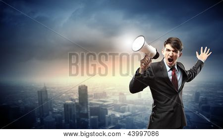 Picture or Photo of Young businessman in black suit screaming into megaphone