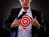 image of on target  - Young business man showing a target under his shirt on dark background - JPG 