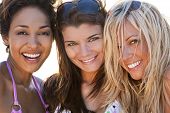 stock photo of laughing  - Three beautiful young women in their twenties laughing and having fun at a beach shot in golden evening sunshine - JPG 